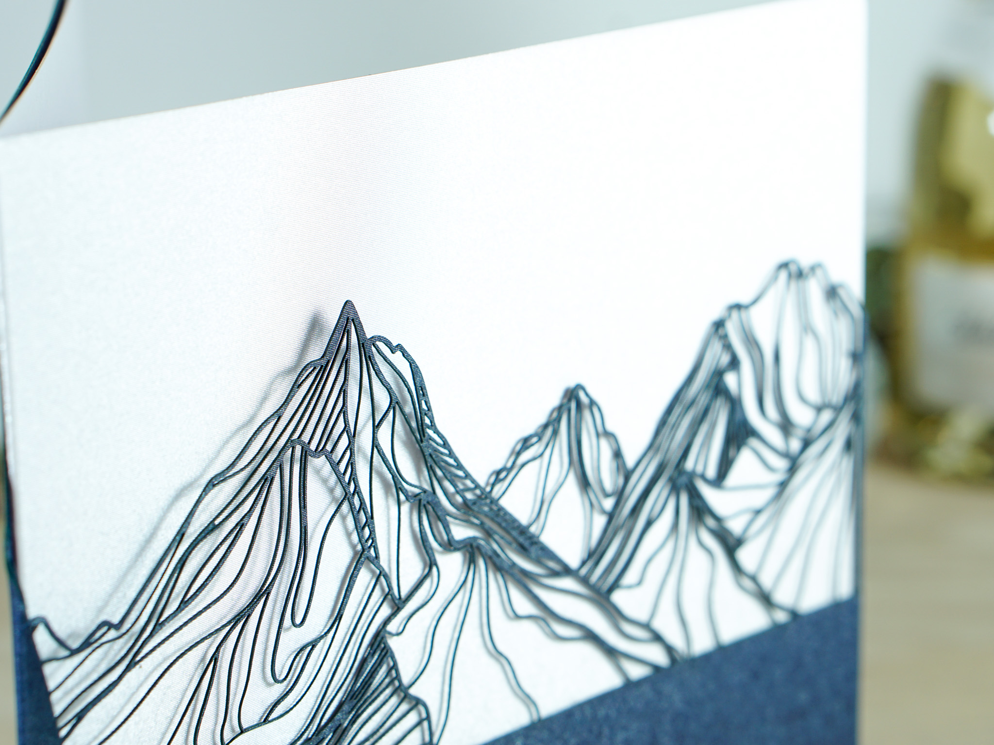PALUXA_Bergkette_Nachtblau_detail2.jpg Zoom-In PALUXA Lasercut-Glückwunschkarte mit Bergkette-Motiv, dunkelblaues Papier, seitlich stehend.