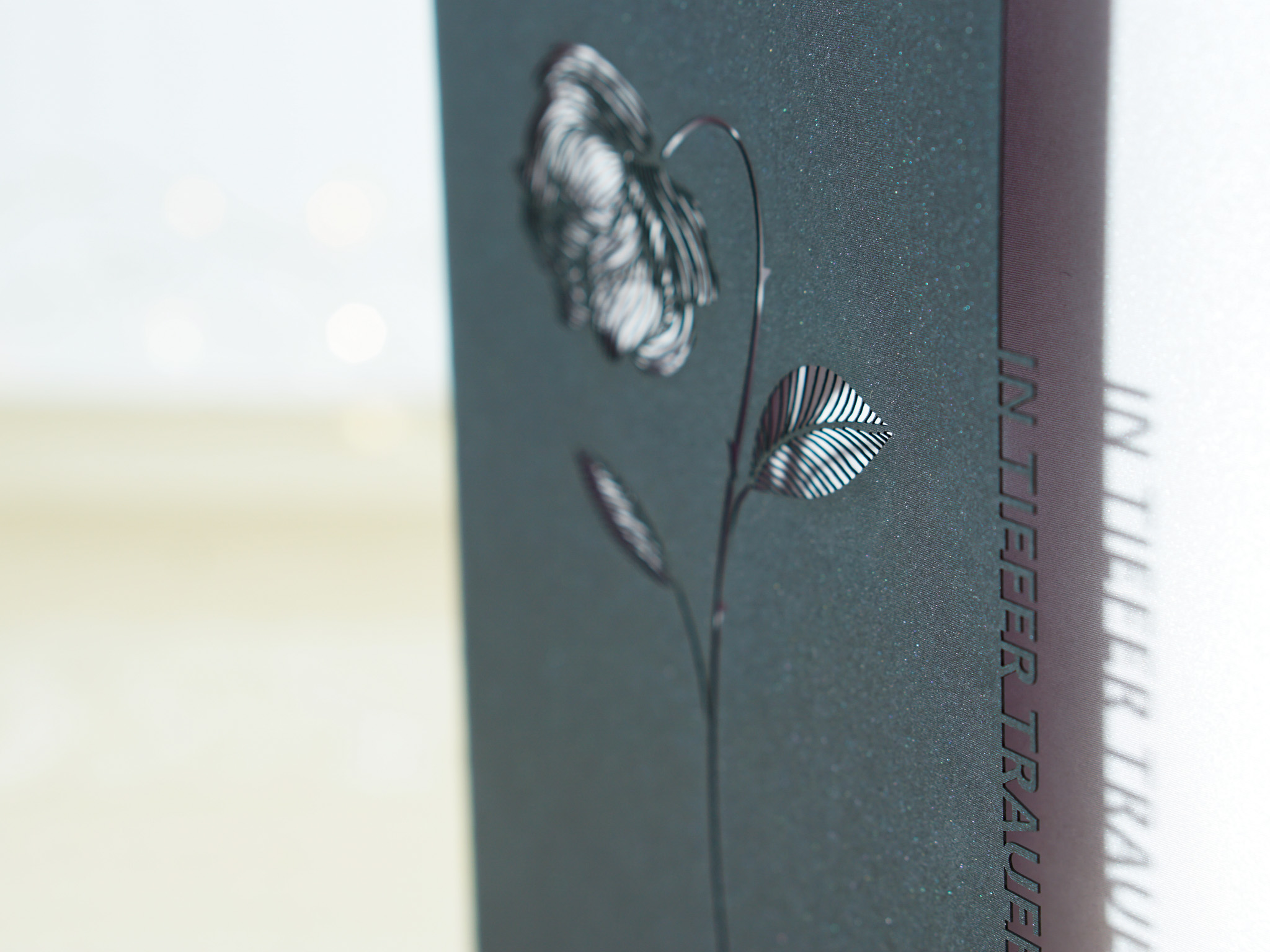 PALUXA_In_tiefer_Trauer_ShinyBlack_detail2.jpg Zoom-In PALUXA Lasercut-Beileidskarte mit Rosen-Motiv, schwarzes Papier, seitlich.