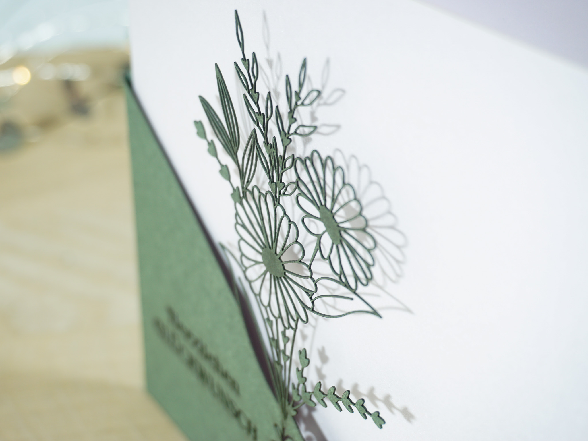 PALUXA_Margeritenstrauss_Tannengruen_detail1.jpg Zoom-In PALUXA Lasercut-Glückwunschkarte mit Margeritenstrauß-Motiv, grünes Papier, stehend.