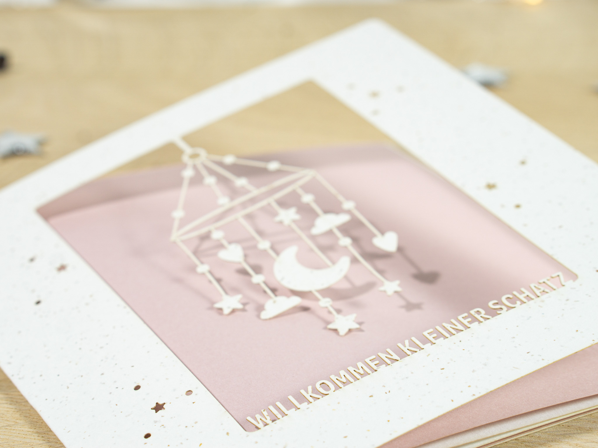 PALUXA_Mobile_MistyRose_detail1.jpg Zoom-In PALUXA Lasercut-Babykarte mit Mobile-Motiv, rosa Einlageblatt, liegend.