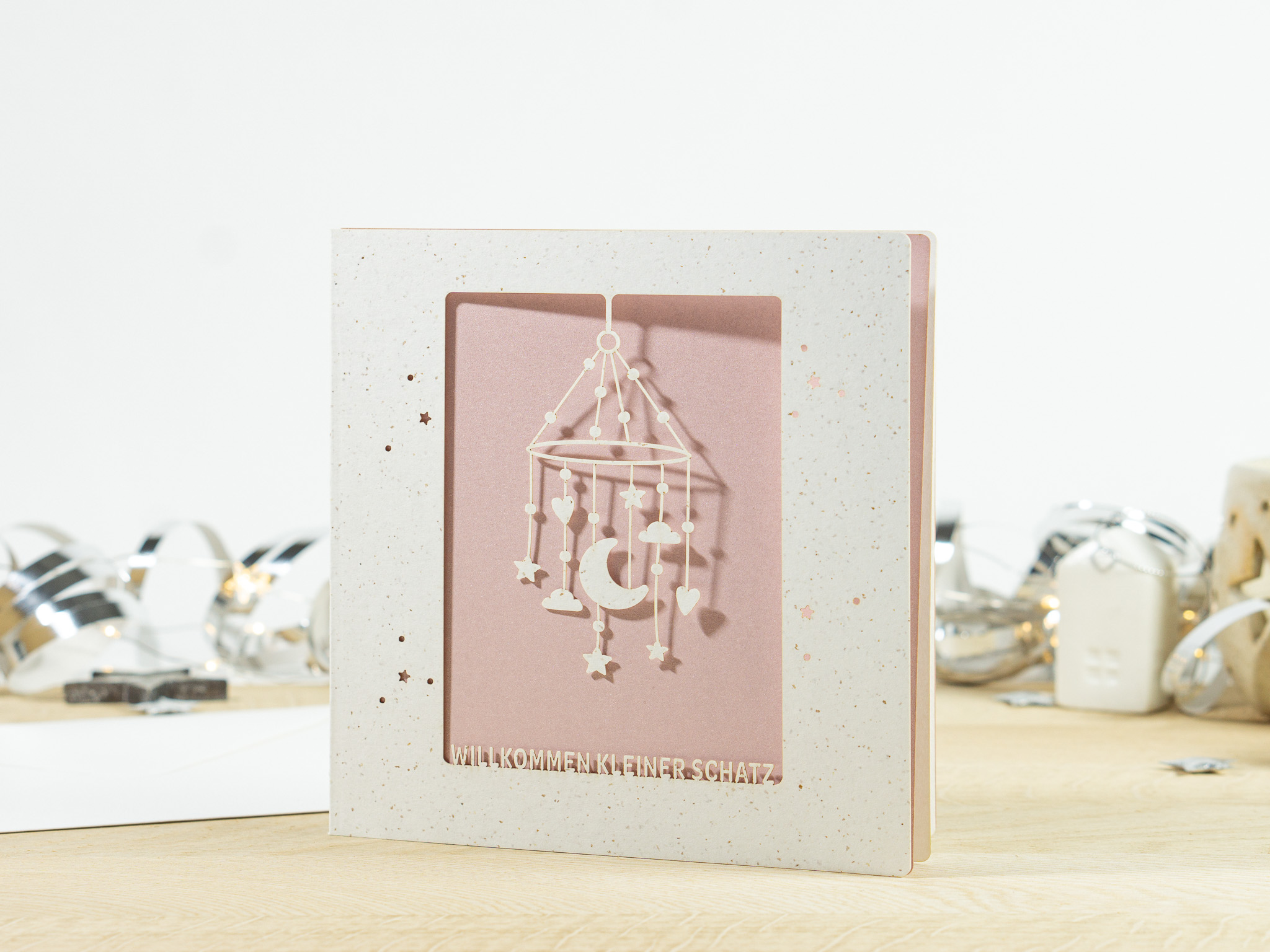 PALUXA_Mobile_MistyRose_stehend.jpg PALUXA Lasercut-Babykarte mit Mobile-Motiv, rosa Einlageblatt, stehend.