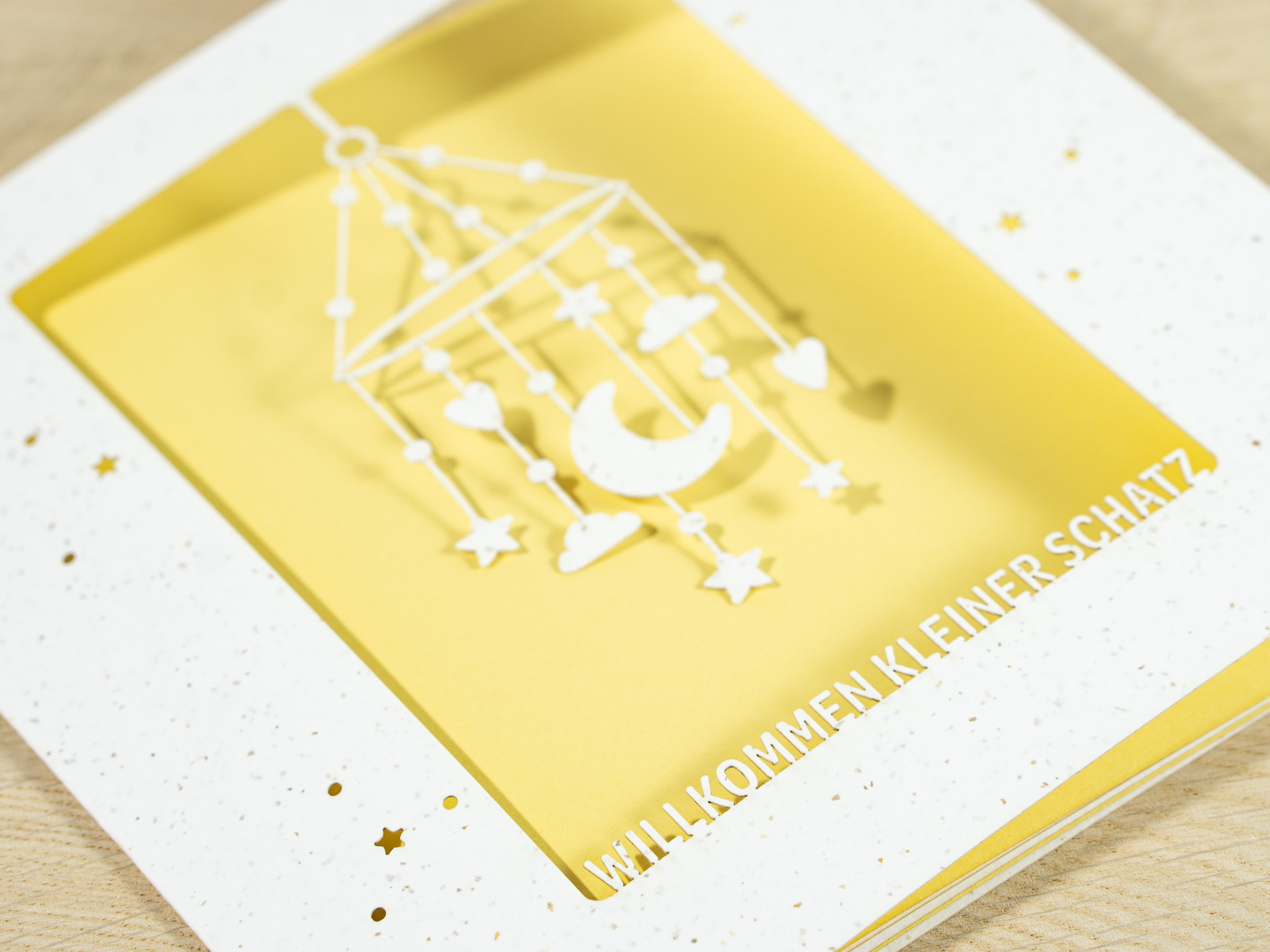 Zoom-In PALUXA Lasercut-Babykarte mit Mobile-Motiv, gelbes Einlageblatt, liegend.