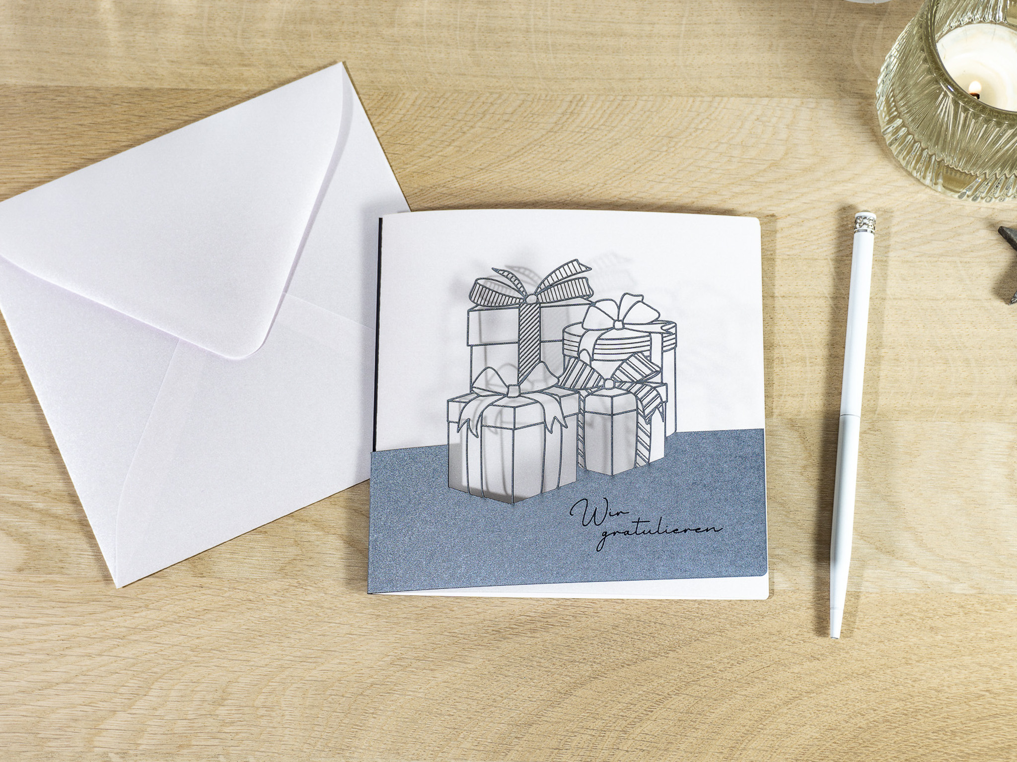 PALUXA_Geschenke_Zinnblau_birdview.jpg PALUXA Lasercut-Glückwunschkarte mit Geschenk Motiv, silbernes Außenblatt, liegend.