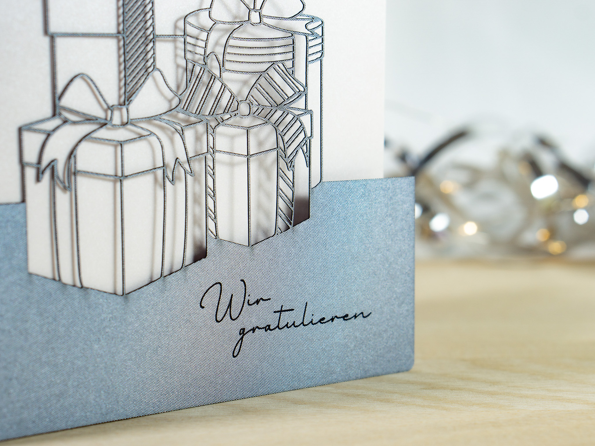 PALUXA_Geschenke_Zinnblau_detail1.jpg Zoom-In PALUXA Lasercut-Glückwunschkarte mit Geschenk Motiv, silbernes Außenblatt, Gravur.