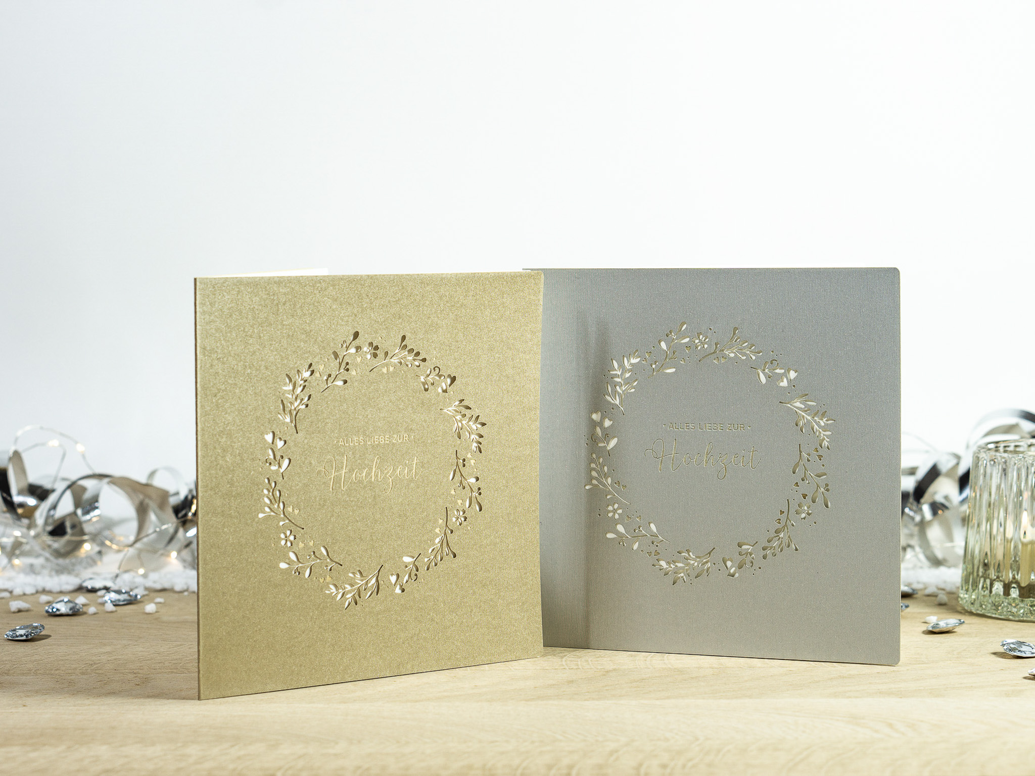 Zwei Farbvarianten PALUXA Lasercut-Hochzeitskarte Gravur mit Kranz, golden und silber, stehend.