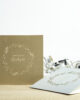 PALUXA_Herzlicher_Kranz_zur_Hochzeit_Varianten1.jpg Zwei Farbvarianten PALUXA Lasercut-Hochzeitskarte Gravur mit Kranz, golden und silber.