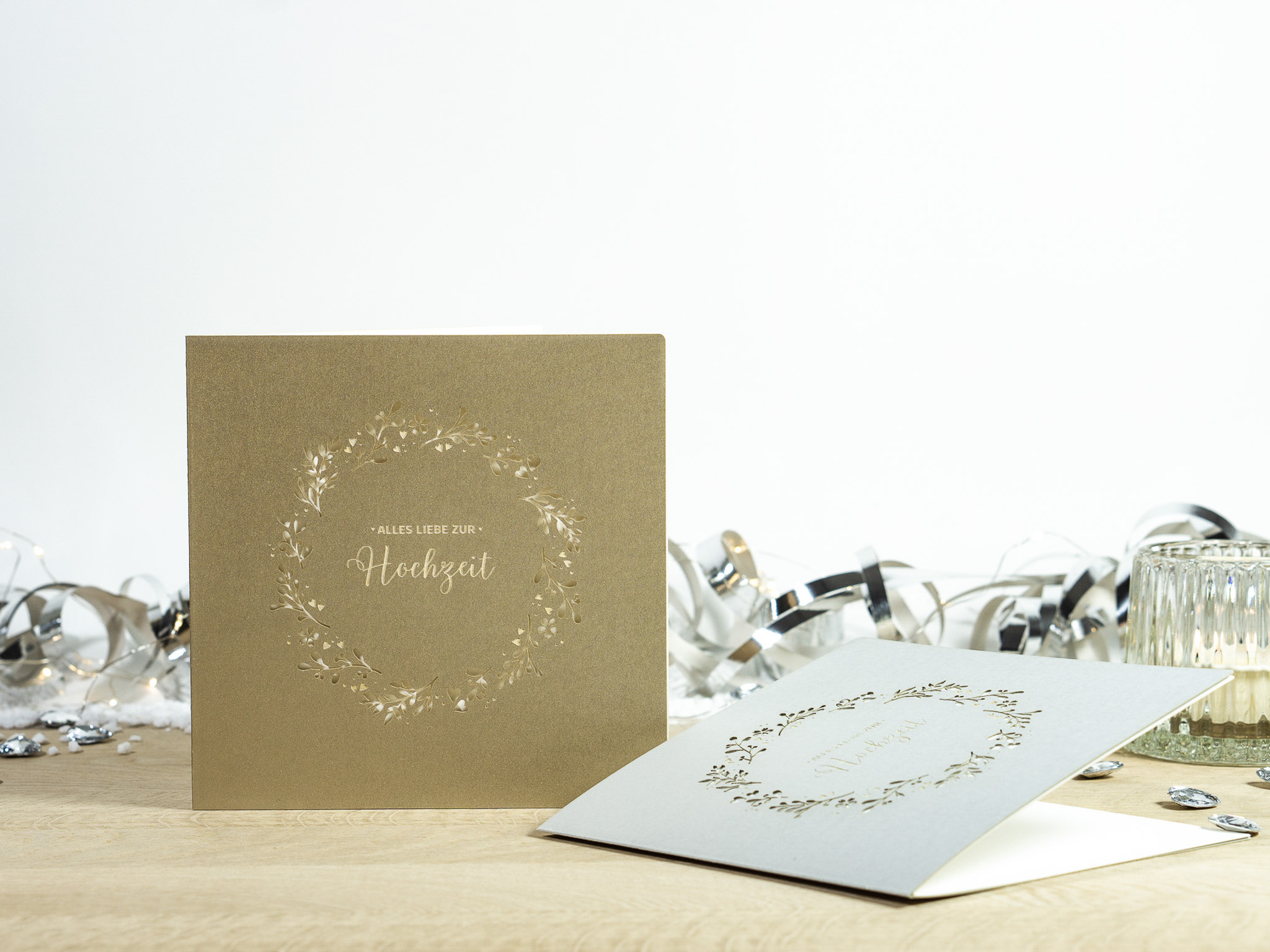 Zwei Farbvarianten PALUXA Lasercut-Hochzeitskarte Gravur mit Kranz, golden und silber.