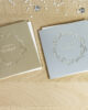 PALUXA_Herzlicher_Kranz_zur_Hochzeit_Varianten_birdview.jpg Zwei Farbvarianten PALUXA Lasercut-Hochzeitskarte Gravur mit Kranz, golden und silber, liegend.