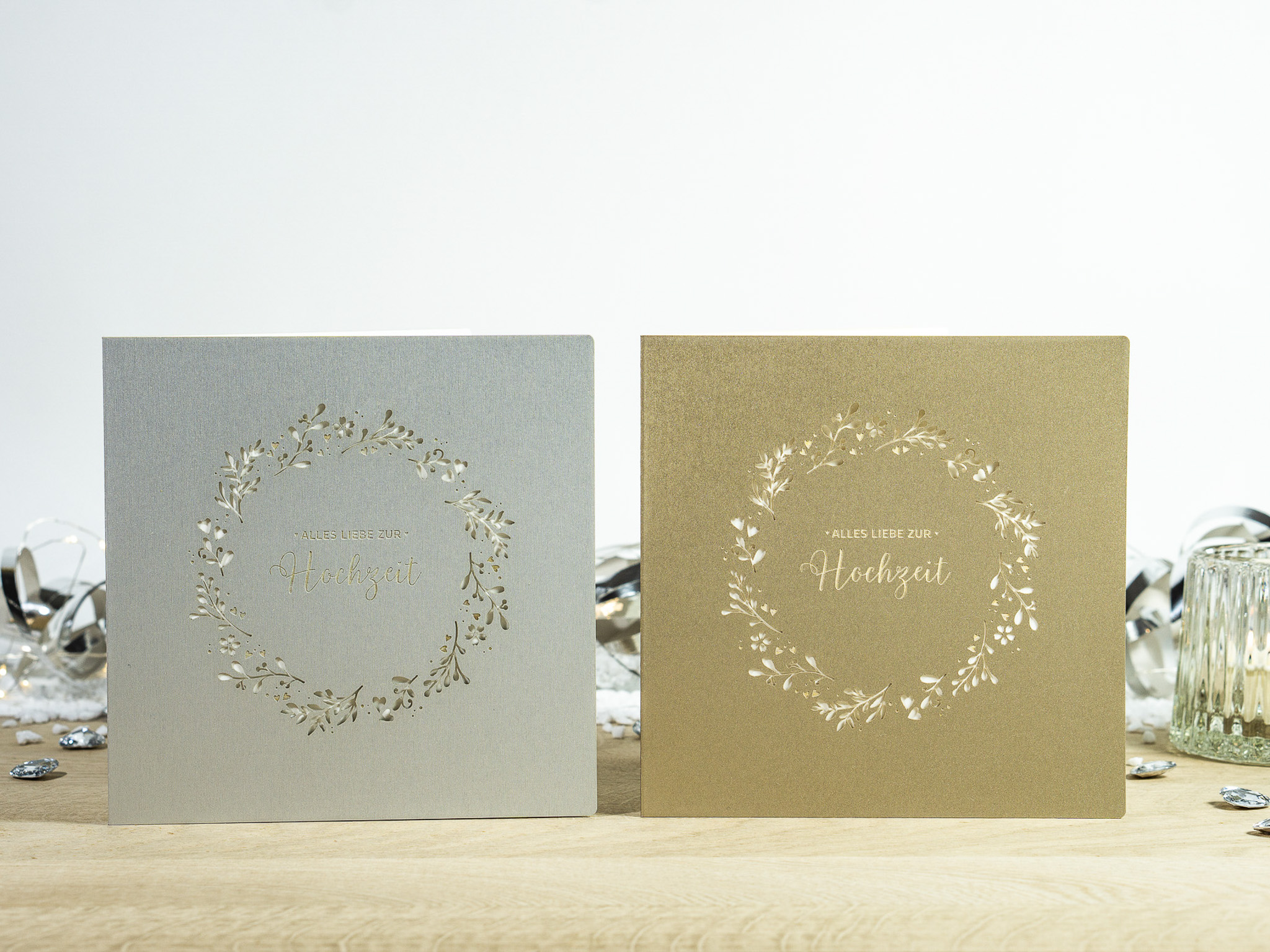 Zwei Farbvarianten PALUXA Lasercut-Hochzeitskarte Gravur mit Kranz, golden und silber, stehend.